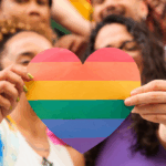 Two women holding up a pride heart