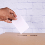 A hand putting a ballot into a ballot box