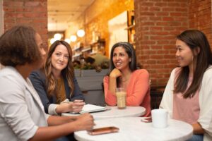 four women sitting next to each other at a table