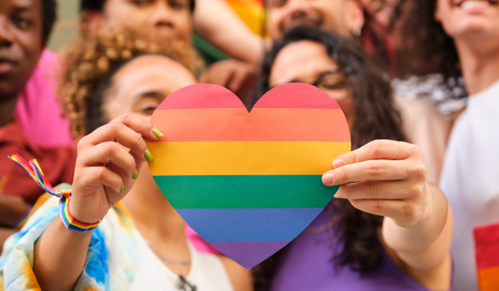 Two women holding up a pride heart