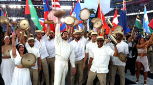 Bad Bunny standing with other men dressed in white shirts holding flags from Americas
