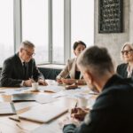 people sitting around boardroom table reviewing paper
