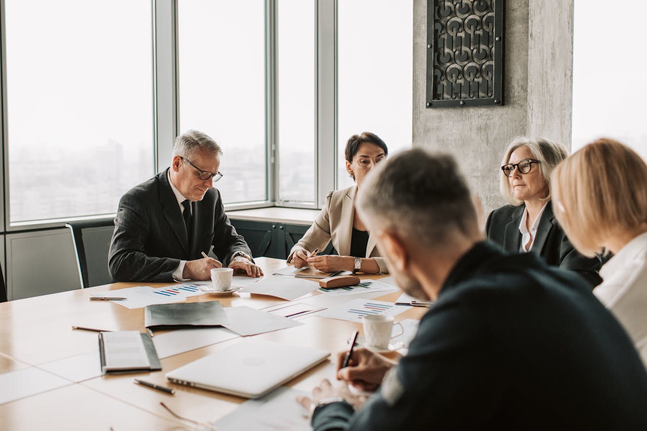 people sitting around boardroom table reviewing paper