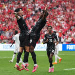 Football players celebrating a goal during an international soccer tournament, highlighting teamwork, achievement, and a shared sense of belonging.