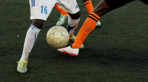 Football players from different teams competing for possession during a soccer match, illustrating teamwork, participation, and inclusion in sport.