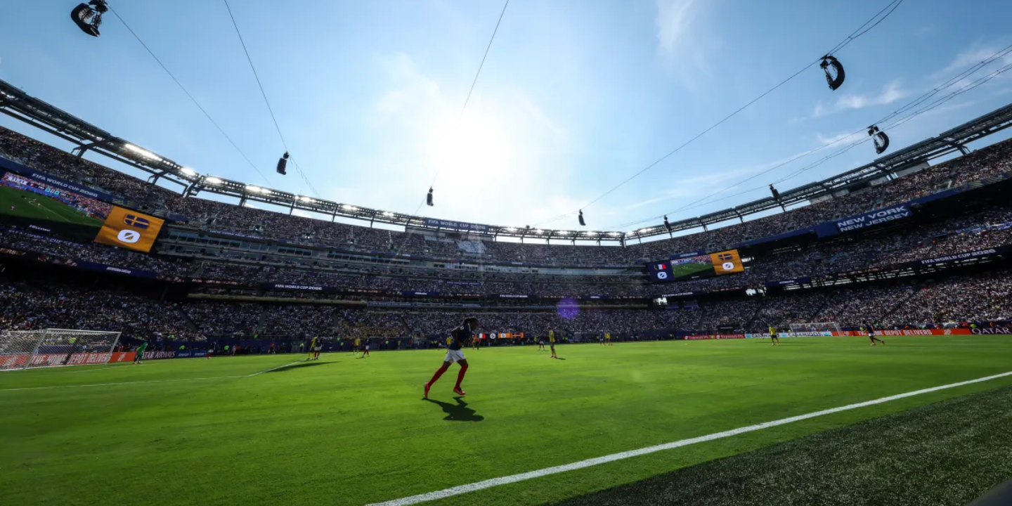 Wide view of a FIFA World Cup match in a packed stadium, with players competing on the field before thousands of supporters.