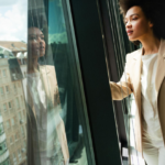 Black business woman looking outside window in office
