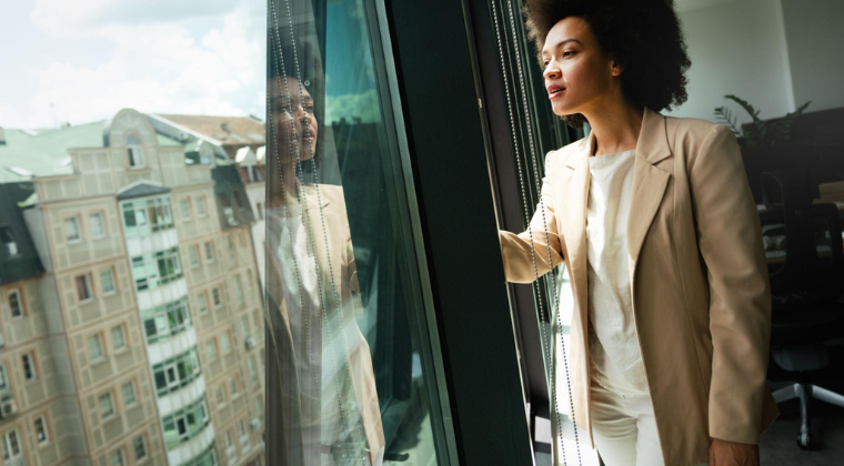 Black business woman looking outside window in office