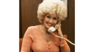 Dolly Parton smiling while speaking on an office telephone in the film 9 to 5.