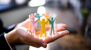 Diverse paper figures held in a hand representing inclusion, belonging and an inclusive workplace culture
