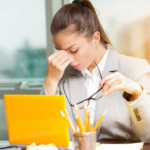Employee experiencing workplace stress and fatigue while working at her desk