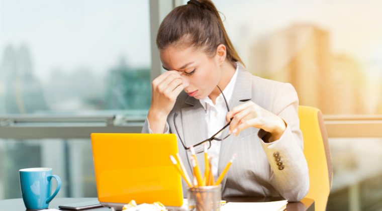 Employee experiencing workplace stress and fatigue while working at her desk